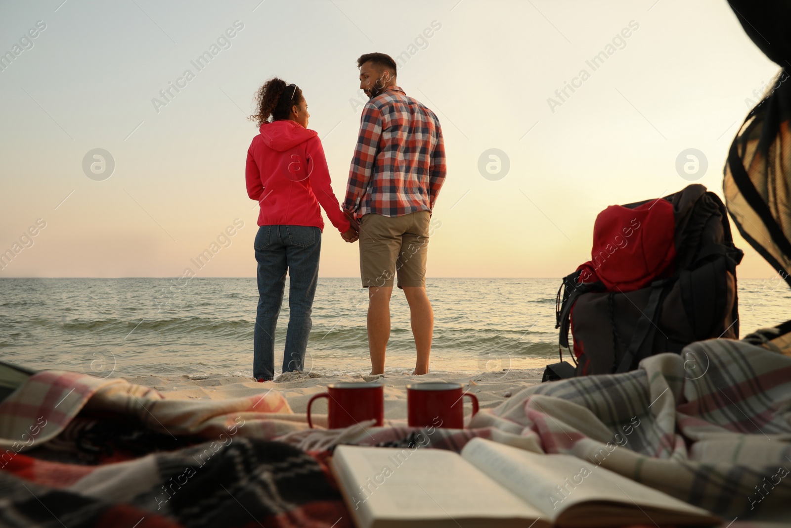 Photo of Couple near sea at sunset, view from camping tent