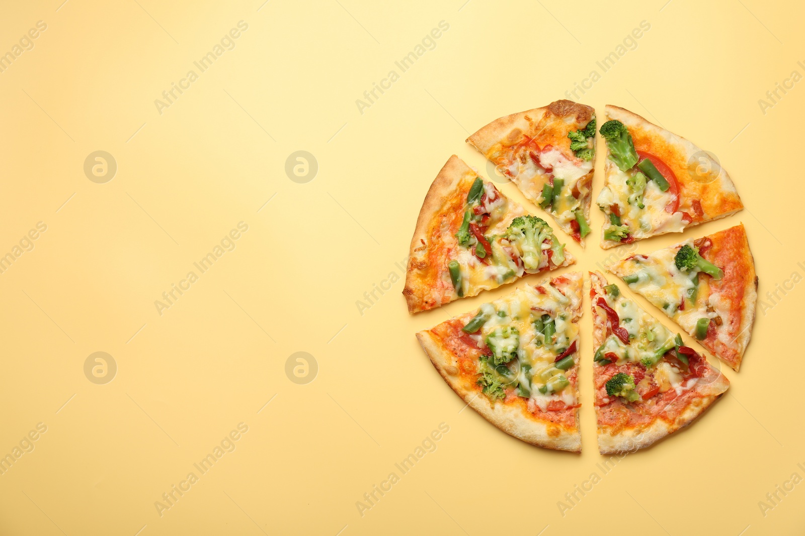 Photo of Delicious vegetarian pizza on yellow table, top view. Space for text