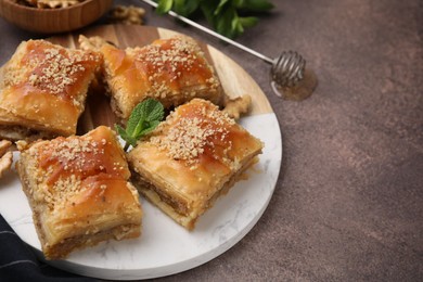 Photo of Eastern sweets. Pieces of tasty baklava on brown table, closeup. Space for text