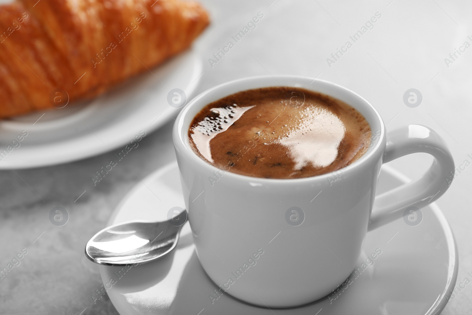 Photo of Cup of fresh coffee and croissant on grey table. Space for text