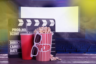 Image of Delicious popcorn, drink, 3D glasses and clapperboard on wooden table in cinema, space for text