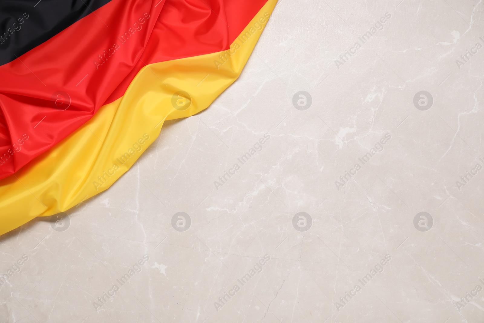 Photo of Flag of Germany on beige marble background, top view. Space for text