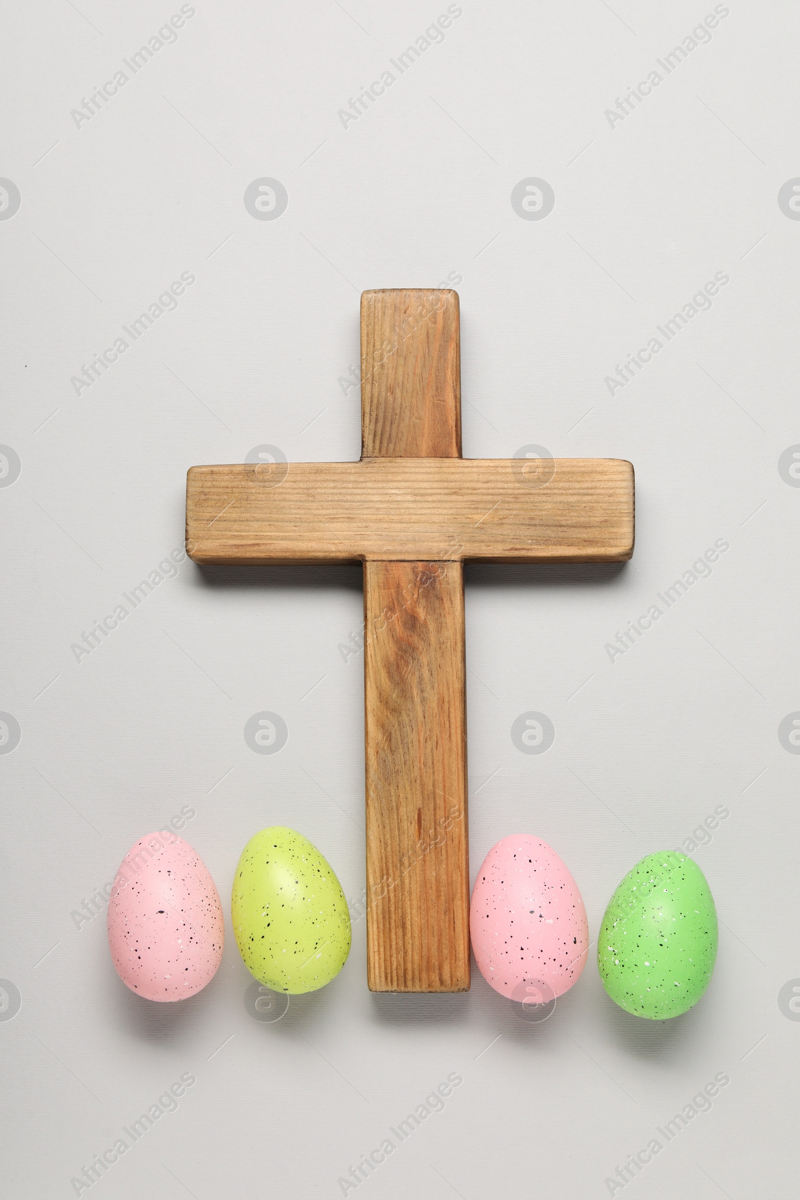 Photo of Wooden cross and painted Easter eggs on light grey background, flat lay