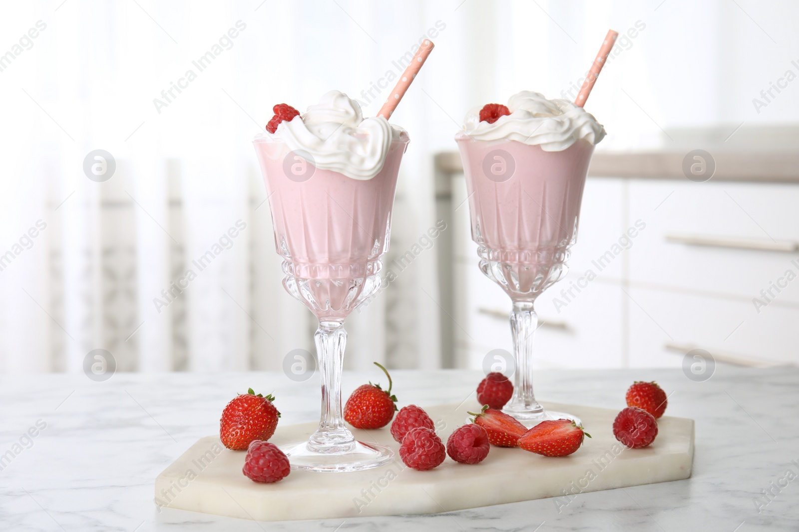 Photo of Tasty milk shake with whipped cream and fresh berries on white marble table