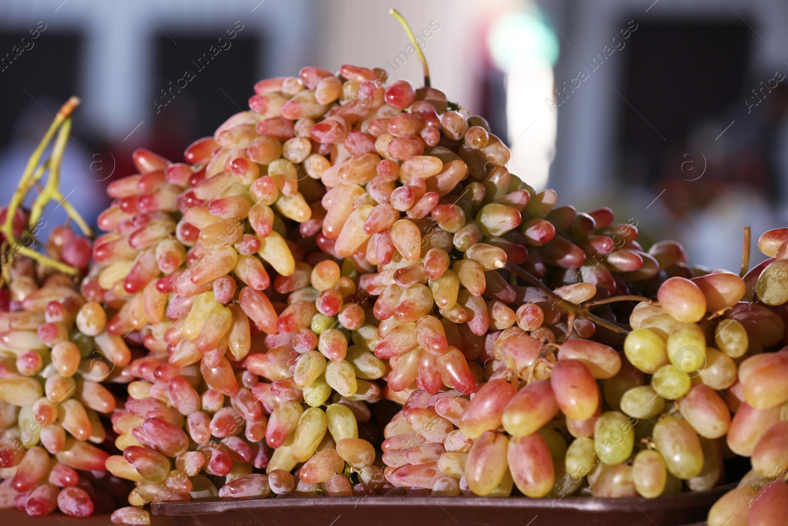 Photo of Fresh ripe juicy grapes on tray against blurred background
