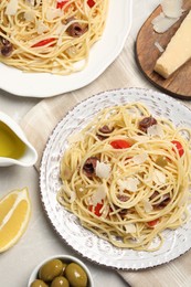 Delicious pasta with anchovies, tomatoes and parmesan cheese on light grey table, flat lay