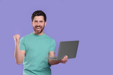 Photo of Emotional man with laptop on purple background. Space for text