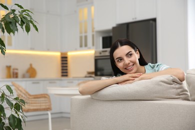 Young woman relaxing on sofa at home, space for text
