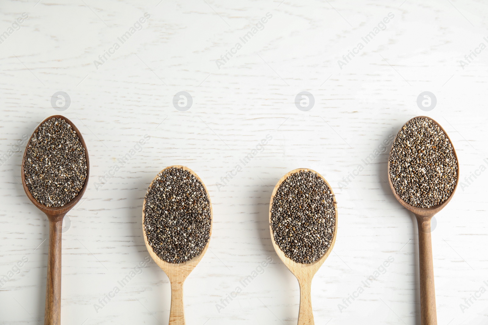 Photo of Spoons with chia seeds on wooden background, flat lay. Space for text