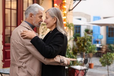 Photo of Affectionate senior couple dancing together on city street, space for text