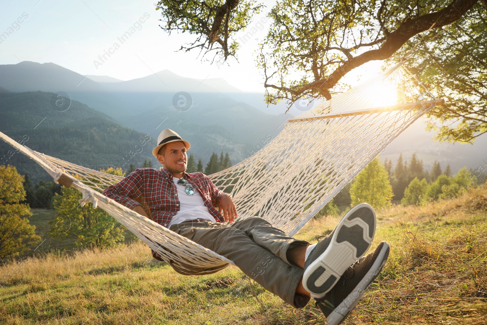 Photo of Man resting in hammock outdoors at sunset