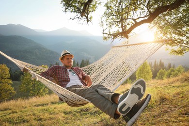 Man resting in hammock outdoors at sunset