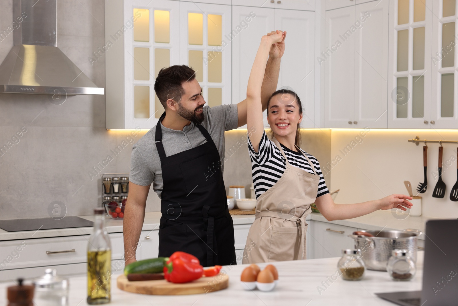 Photo of Happy lovely couple dancing together while cooking in kitchen