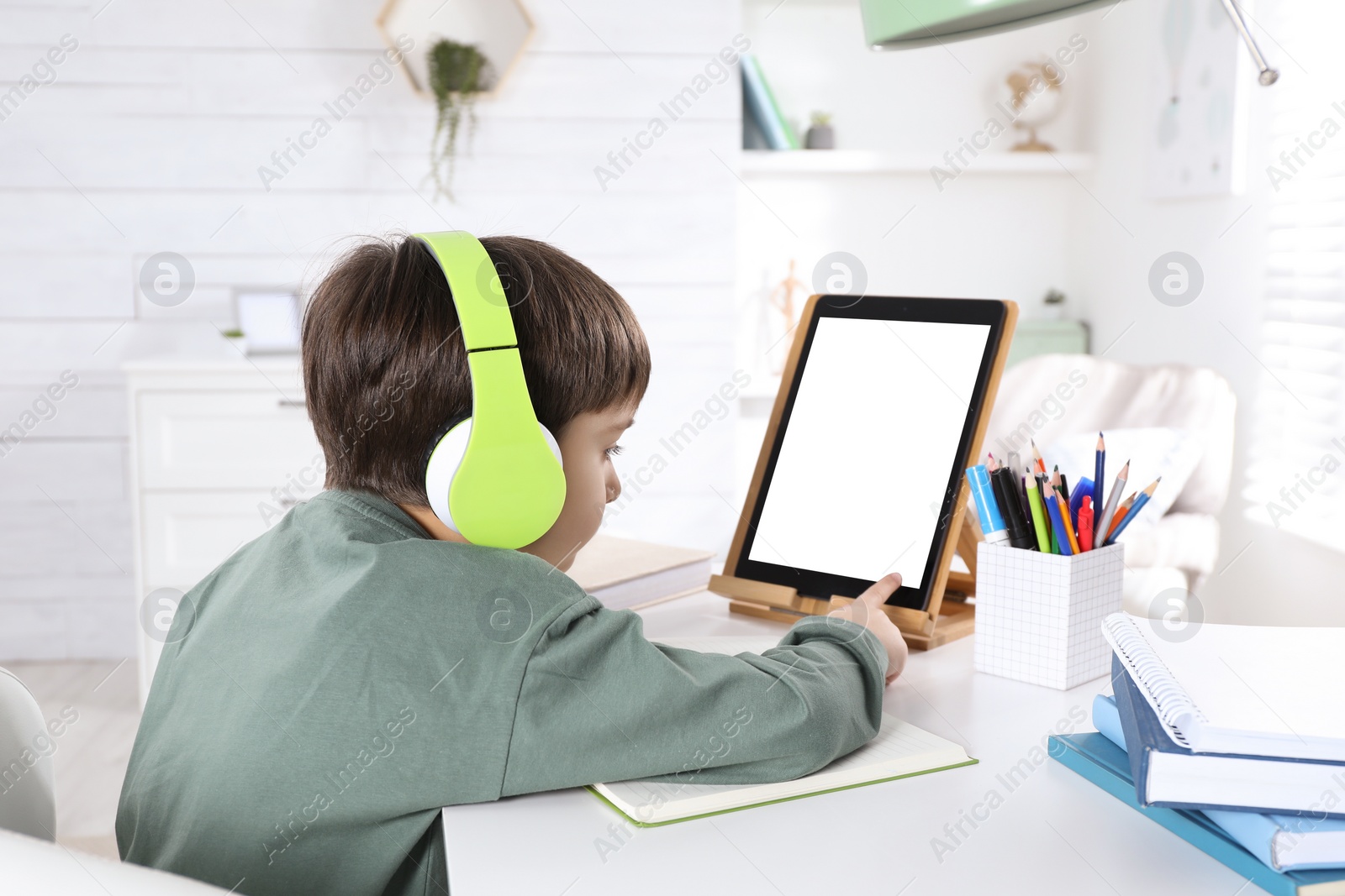 Photo of Cute little boy with modern tablet studying online at home. E-learning