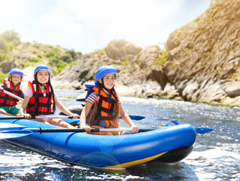 School holidays. Group of happy children kayaking on river 