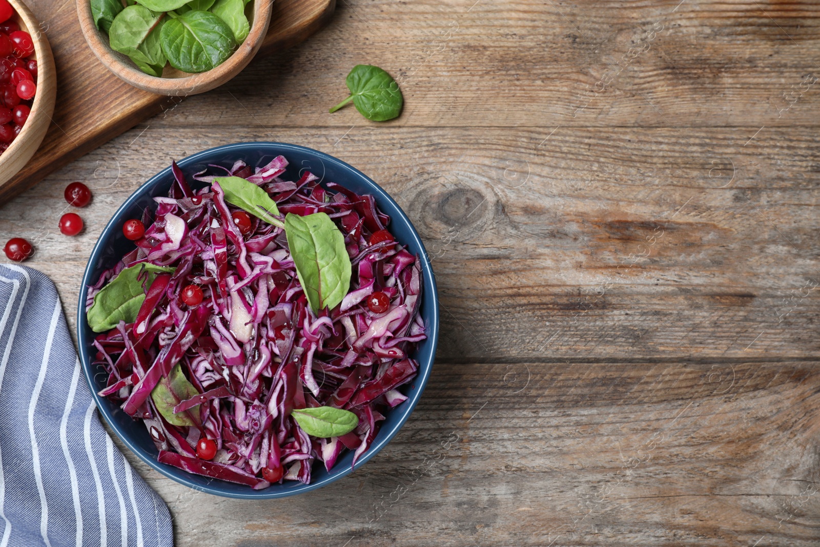 Photo of Fresh red cabbage salad served on wooden table, flat lay. Space for text