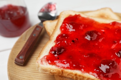 Photo of Toasts with jam on wooden plate, closeup