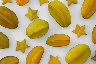 Delicious cut and whole carambolas on white background, top view