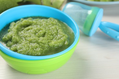 Healthy baby food. Bowl with tasty broccoli puree on white wooden table, closeup and space for text