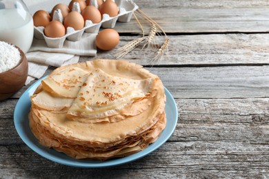 Photo of Delicious crepes and ingredients on wooden table. Space for text