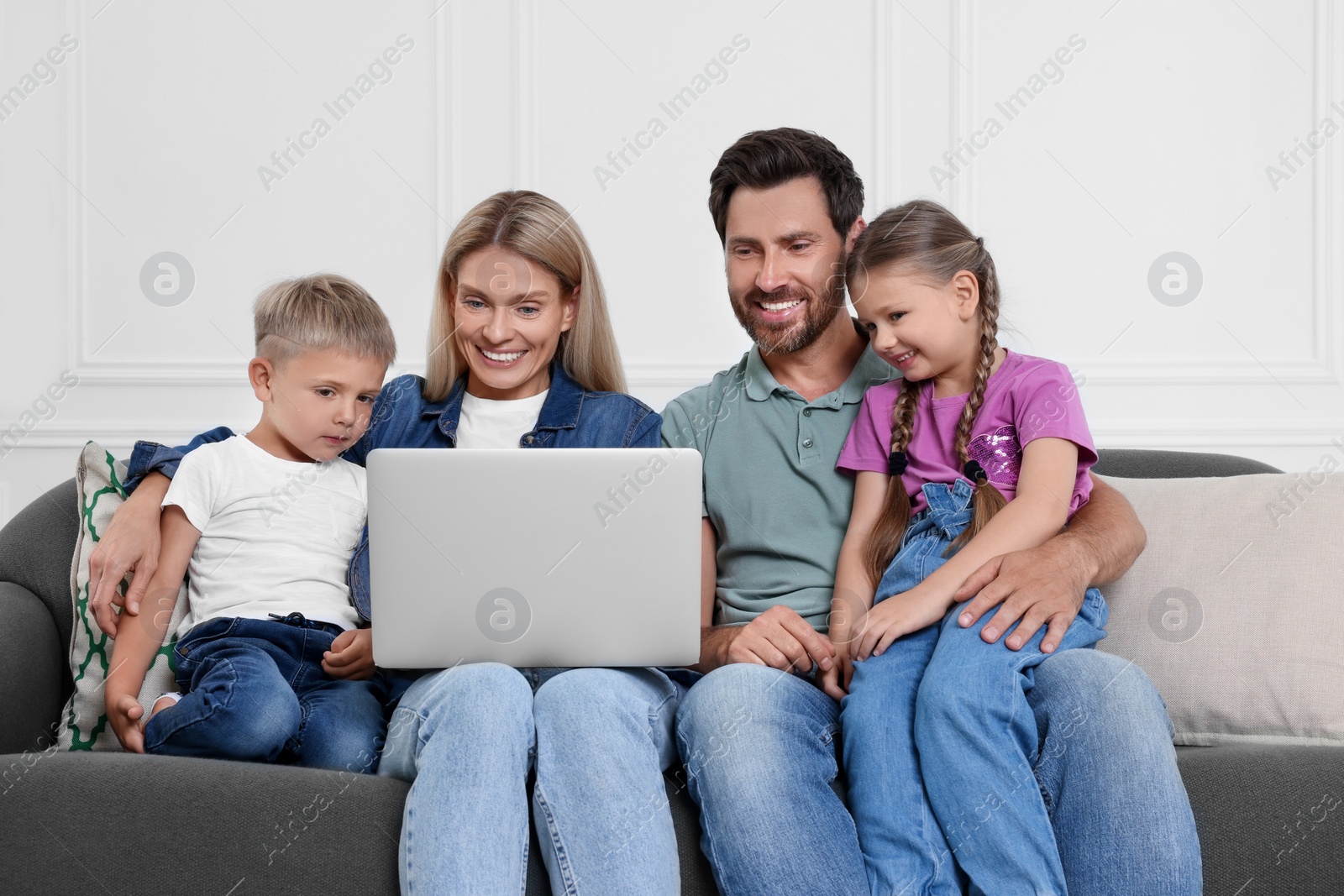 Photo of Happy family with laptop spending time together on sofa at home