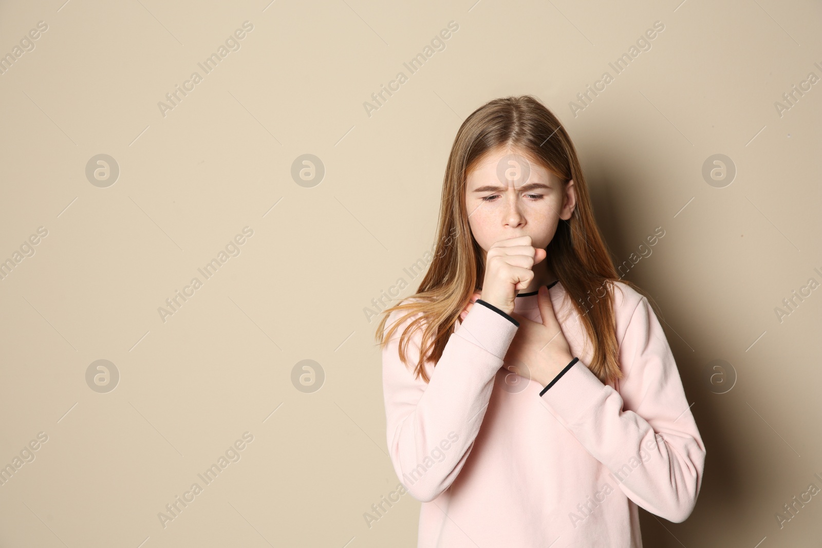 Photo of Teenage girl suffering from cough on color background. Space for text