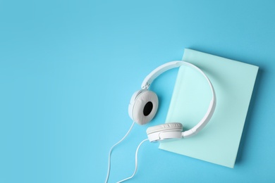Photo of Modern headphones with hardcover book on color background, top view. Space for text