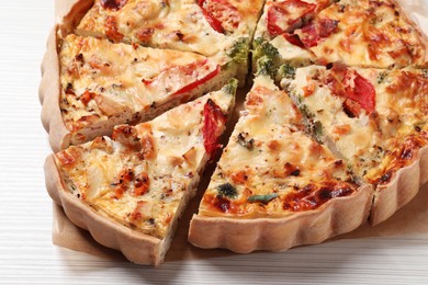 Photo of Tasty quiche with tomatoes and cheese on white wooden table, closeup