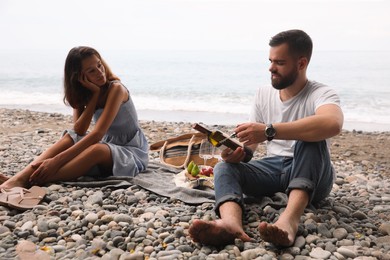 Young couple having picnic on beach near sea