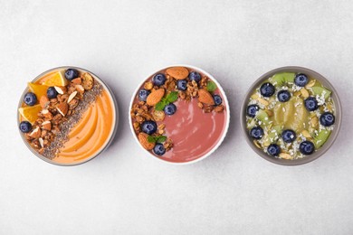 Bowls with different delicious fruit smoothies on white background, flat lay