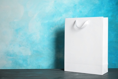 Photo of Paper shopping bag on table against color background. Mock up for design