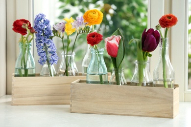 Beautiful spring flowers in wooden crates on window sill
