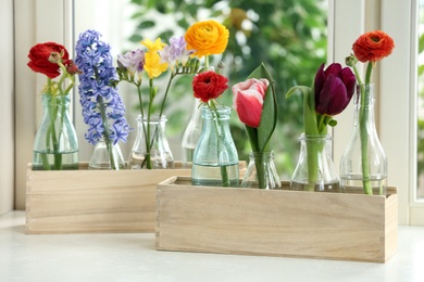 Photo of Beautiful spring flowers in wooden crates on window sill