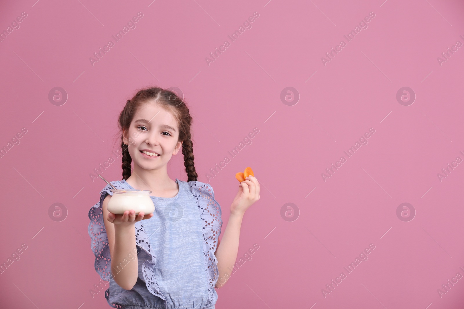 Photo of Cute girl eating tasty yogurt on color background