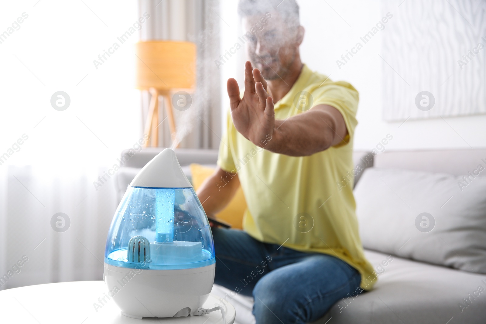 Photo of Man near modern air humidifier at home