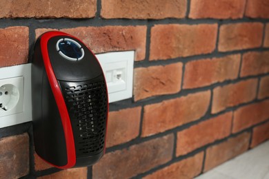 Compact electric heater charging from socket indoors, closeup. Space for text