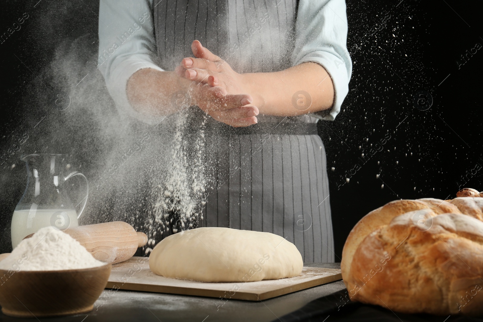 Photo of Female baker preparing bread dough at kitchen table