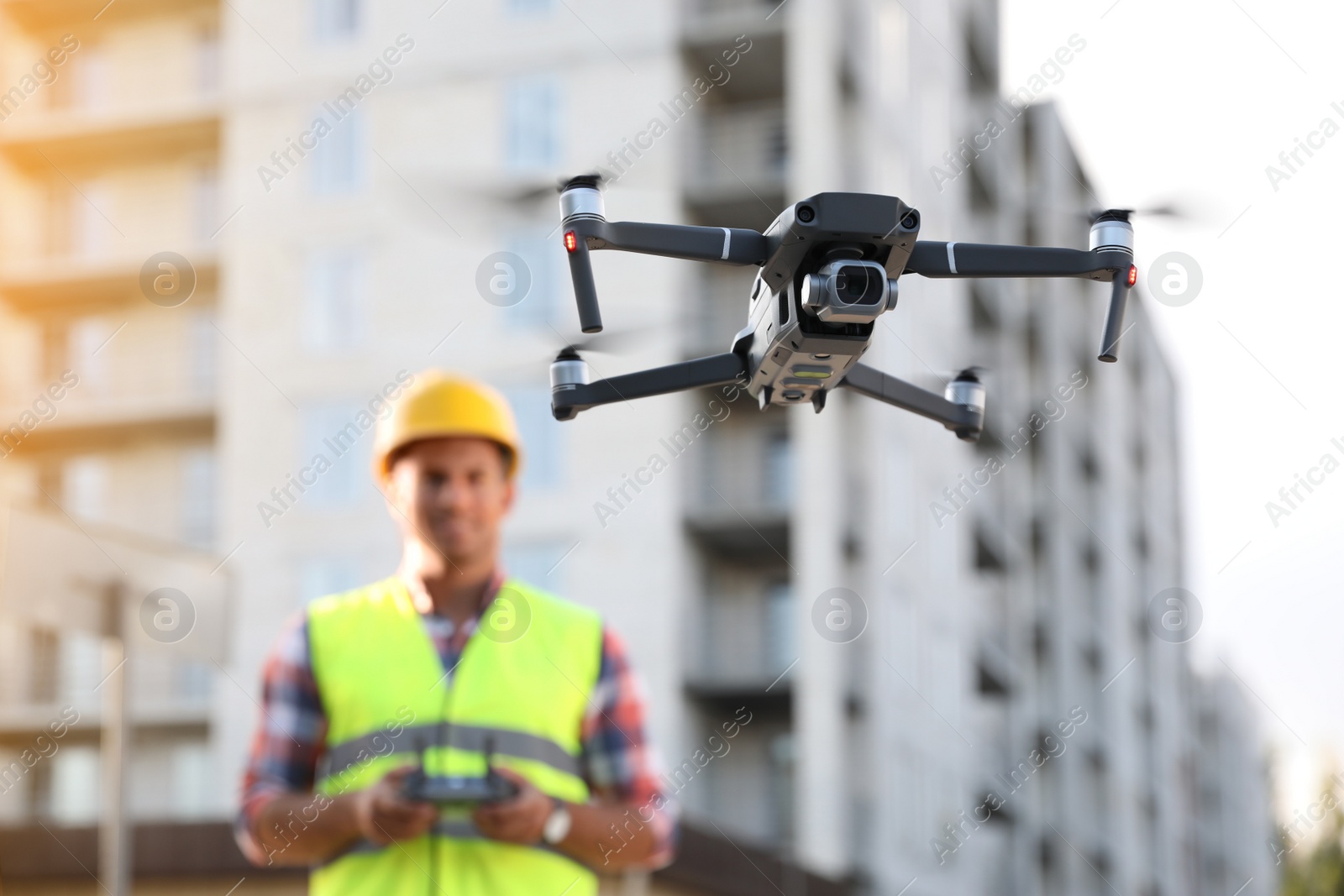 Photo of Builder operating drone with remote control at construction site, focus on quadcopter. Aerial survey