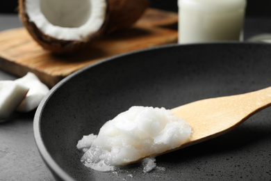 Frying pan with coconut oil and wooden spatula on table, closeup. Healthy cooking