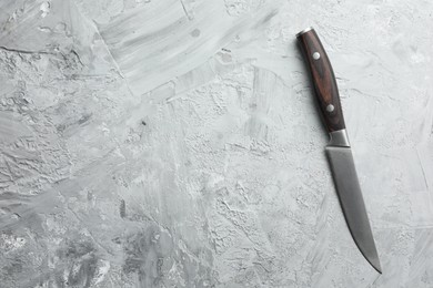 Photo of One knife on grey textured table, top view. Space for text