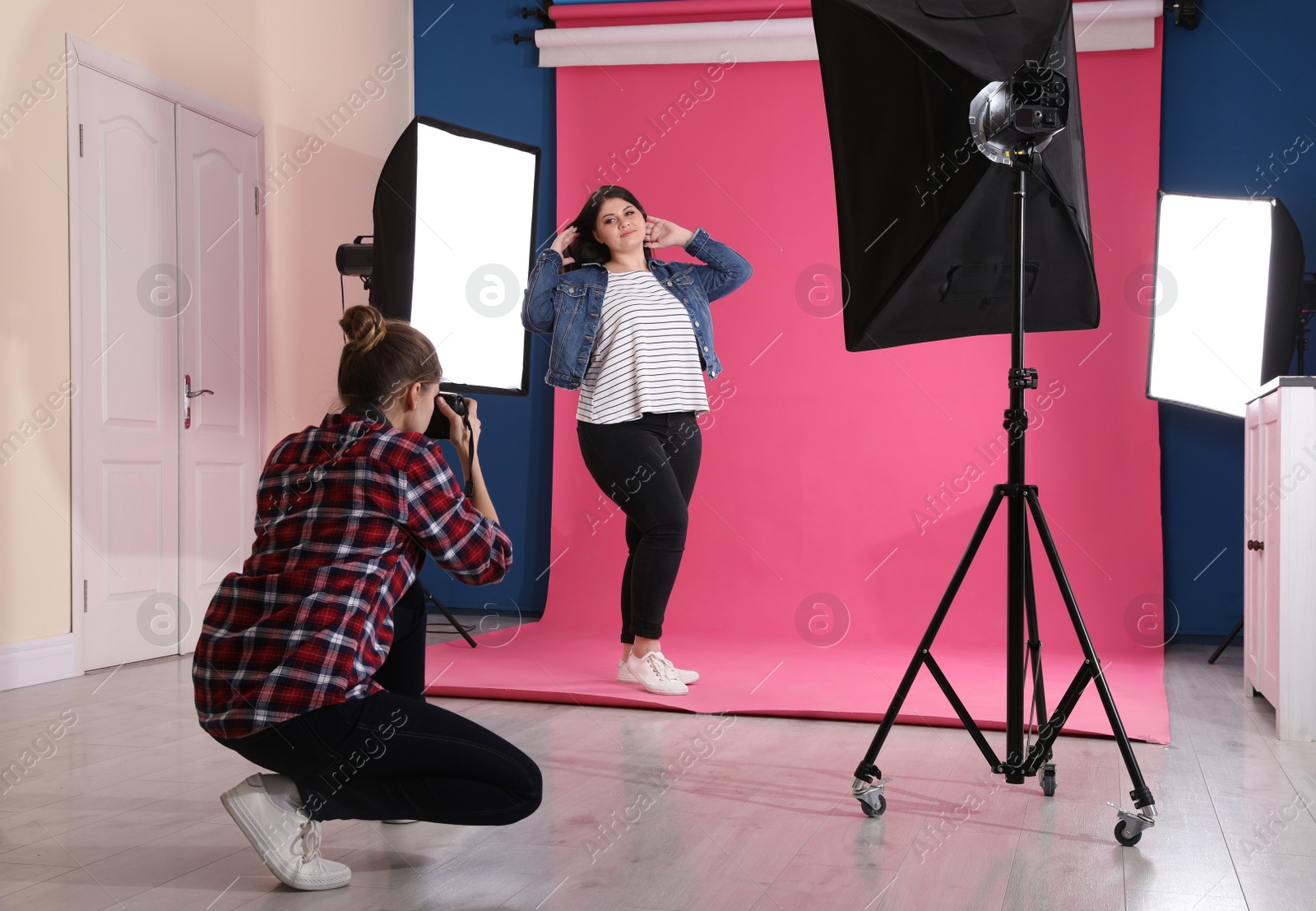 Photo of Photographer taking picture of overweight woman in studio. Plus size model