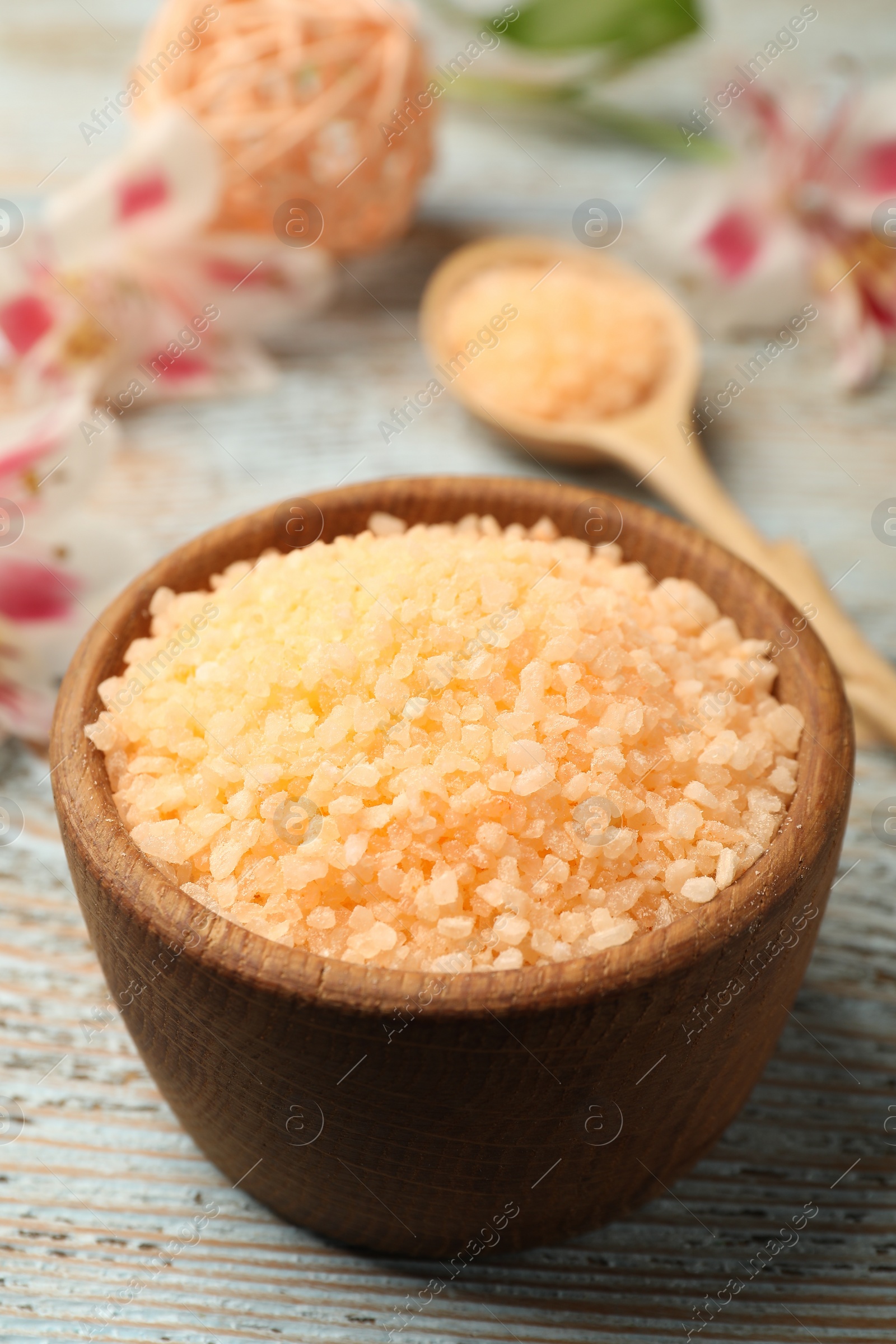 Photo of Orange sea salt in bowl on wooden table, closeup