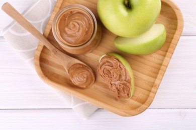 Fresh green apples with peanut butter on white wooden table, top view