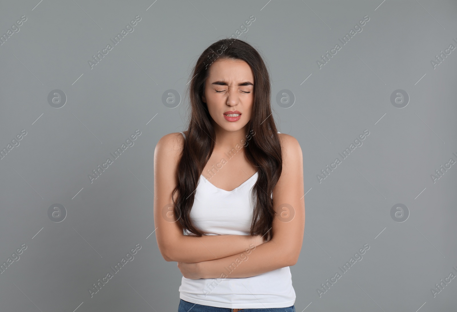 Photo of Young woman suffering from stomach ache on grey background. Food poisoning