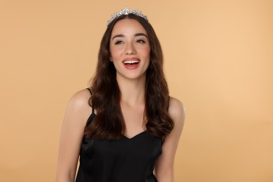 Photo of Beautiful young woman with tiara in stylish dress on beige background