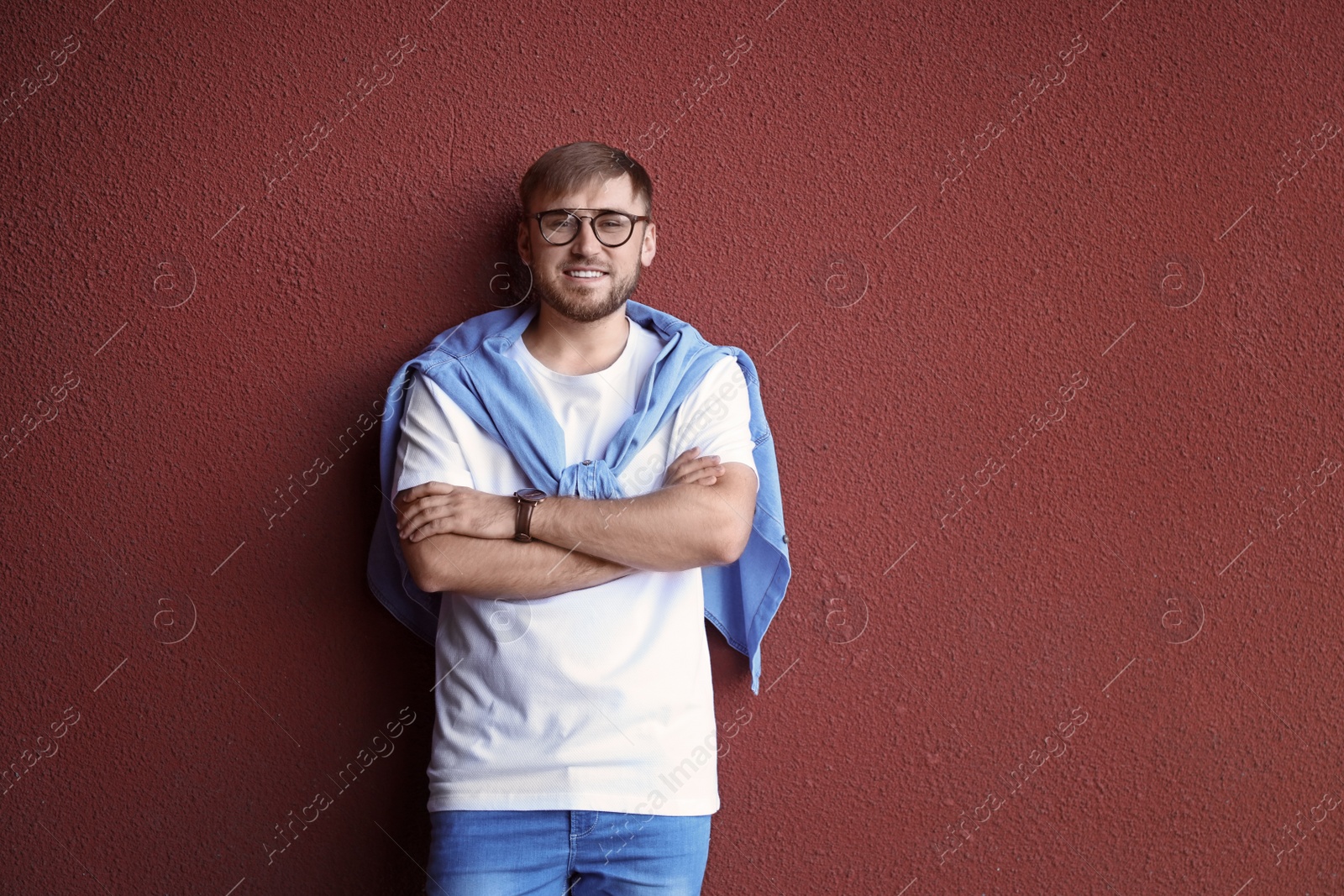 Photo of Young hipster man in stylish jeans posing near color wall