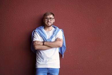 Photo of Young hipster man in stylish jeans posing near color wall