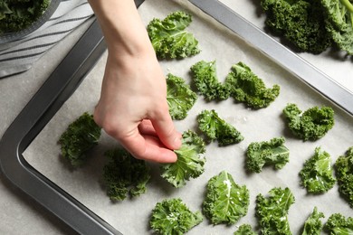 Woman preparing kale chips at table, closeup