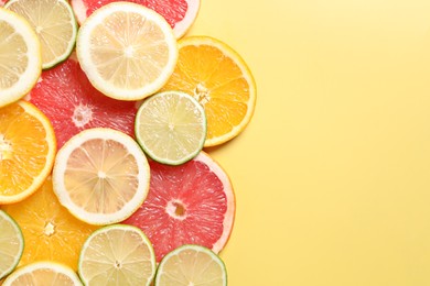 Photo of Different sliced citrus fruits on yellow table, top view. Space for text