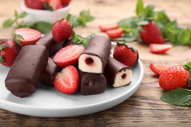 Delicious glazed curd snacks with fresh strawberries and mint on wooden table, closeup